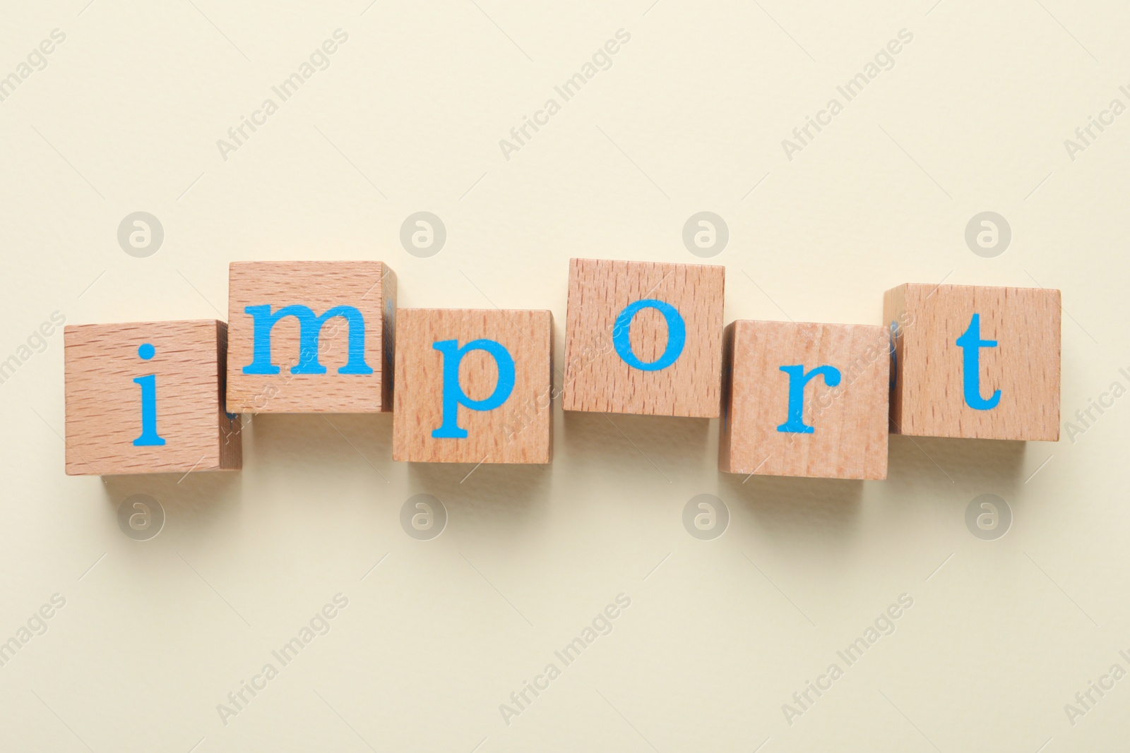 Photo of Word Import made of wooden cubes with letters on beige background, flat lay