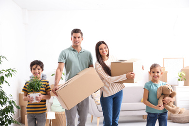 Photo of Happy family in room with cardboard boxes on moving day