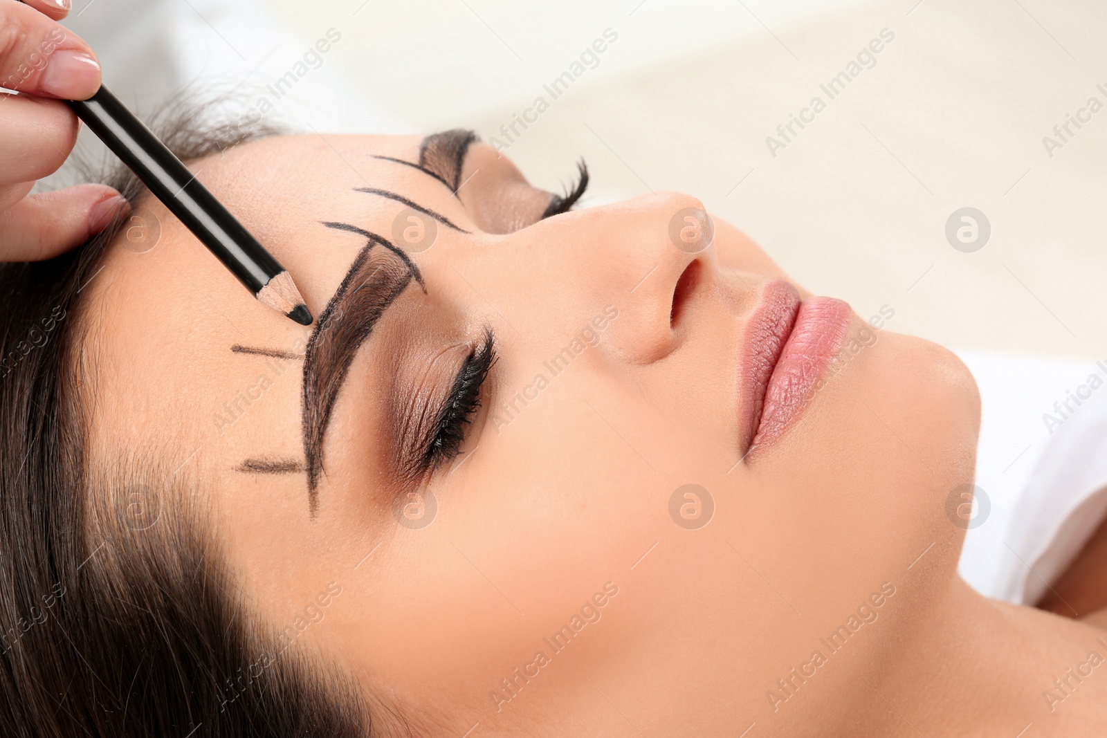 Photo of Cosmetologist preparing young woman for  eyebrow permanent makeup procedure, closeup