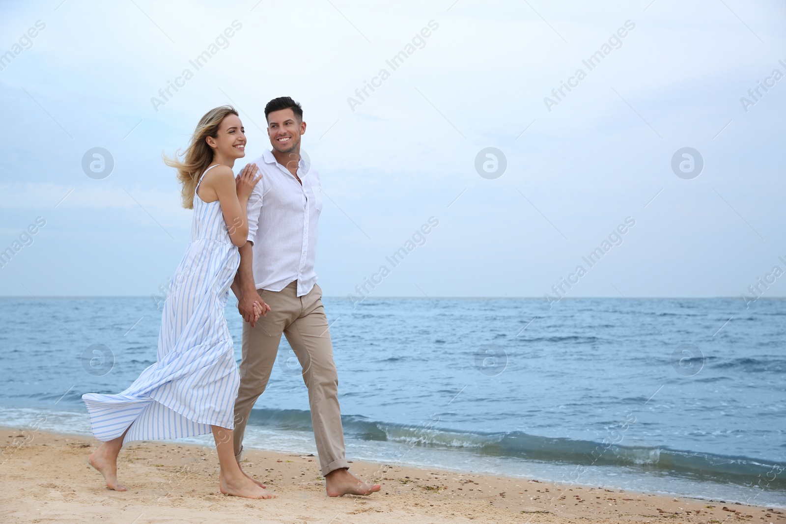 Photo of Happy couple having romantic walk on beach. Space for text