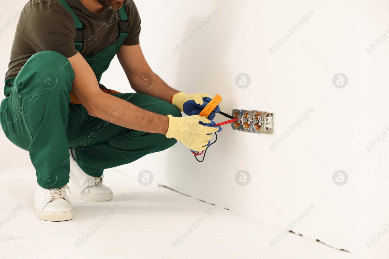 Photo of Electrician with tester checking voltage indoors, closeup