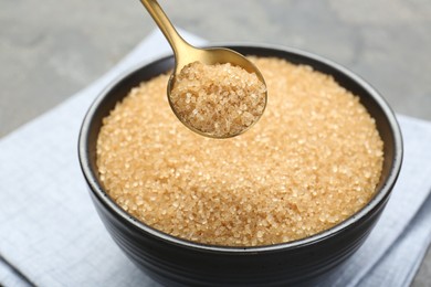 Photo of Taking brown sugar with spoon from bowl at table, closeup