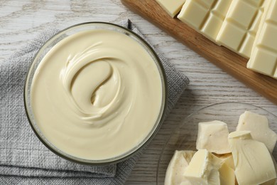 Tasty white chocolate paste in bowl and pieces on table, top view