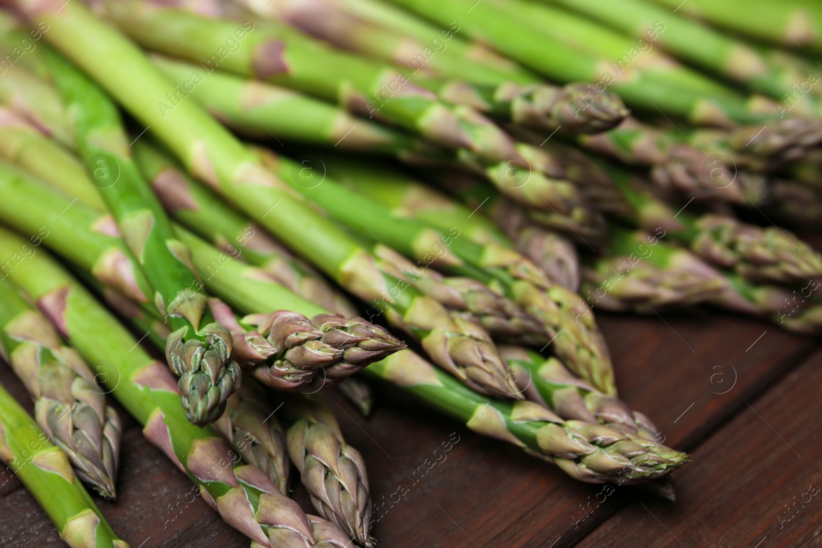 Photo of Fresh raw asparagus on wooden table, closeup
