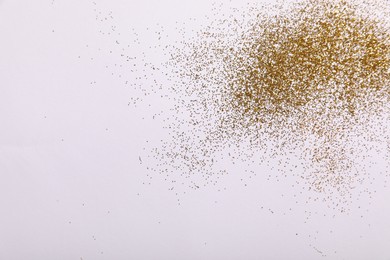 Shiny golden glitter on white background, top view