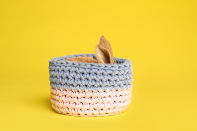 Adorable furry Easter bunny hiding in basket on color background