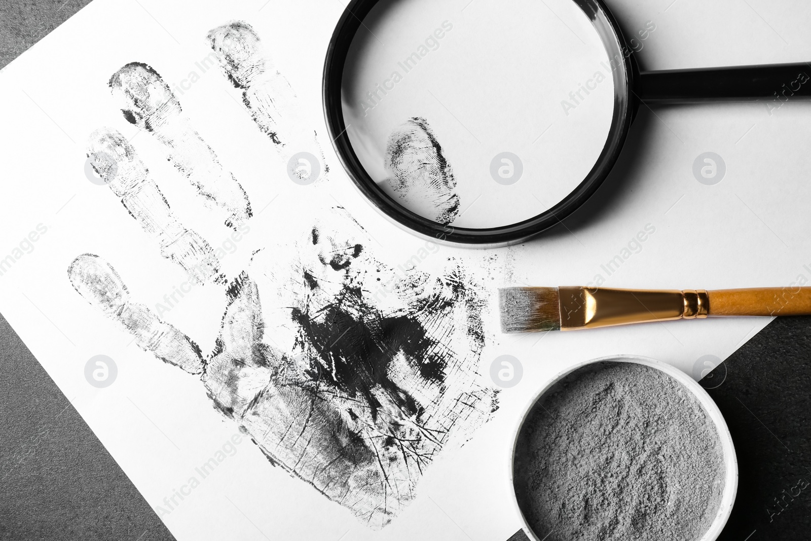 Photo of Magnifying glass and palm print on table, top view. Detective's workplace