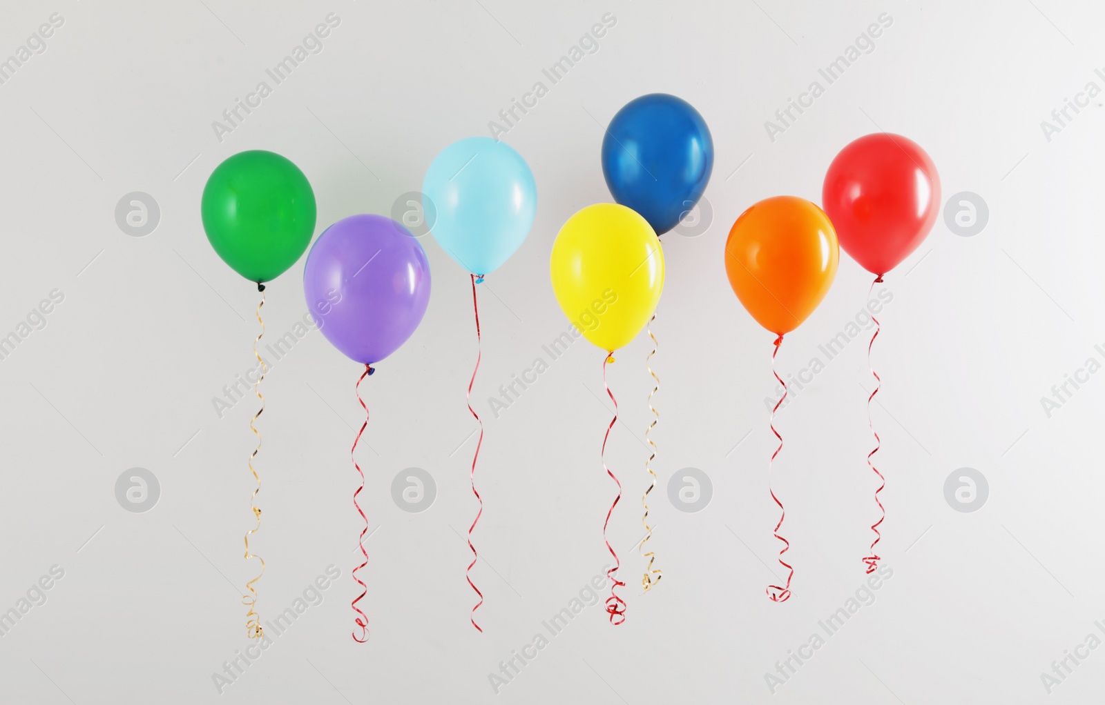 Photo of Different bright balloons on light background. Celebration time