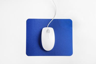 Photo of Modern wired optical mouse and pad on white background, top view