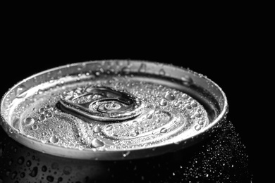 Photo of Aluminum can of beverage covered with water drops on black background, closeup