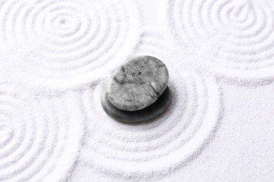 Photo of Zen garden stones on white sand with pattern, above view