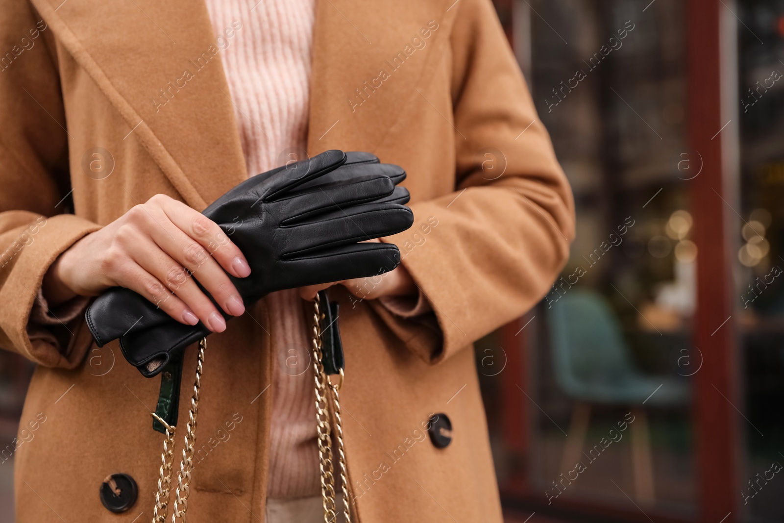 Photo of Young woman holding black leather gloves, closeup. Stylish clothes