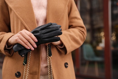 Photo of Young woman holding black leather gloves, closeup. Stylish clothes