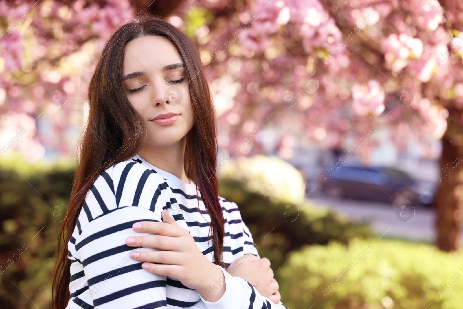 Photo of Beautiful woman near blossoming tree on spring day, space for text