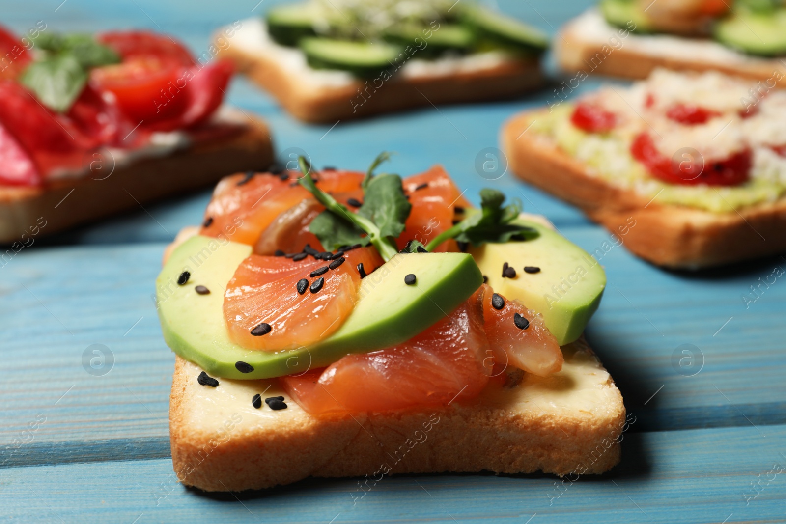 Photo of Tasty toasts with different toppings on light blue wooden table, closeup