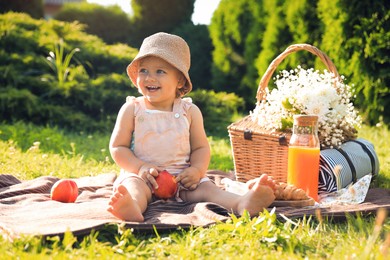 Photo of Cute little baby girl with nectarine on picnic blanket in garden