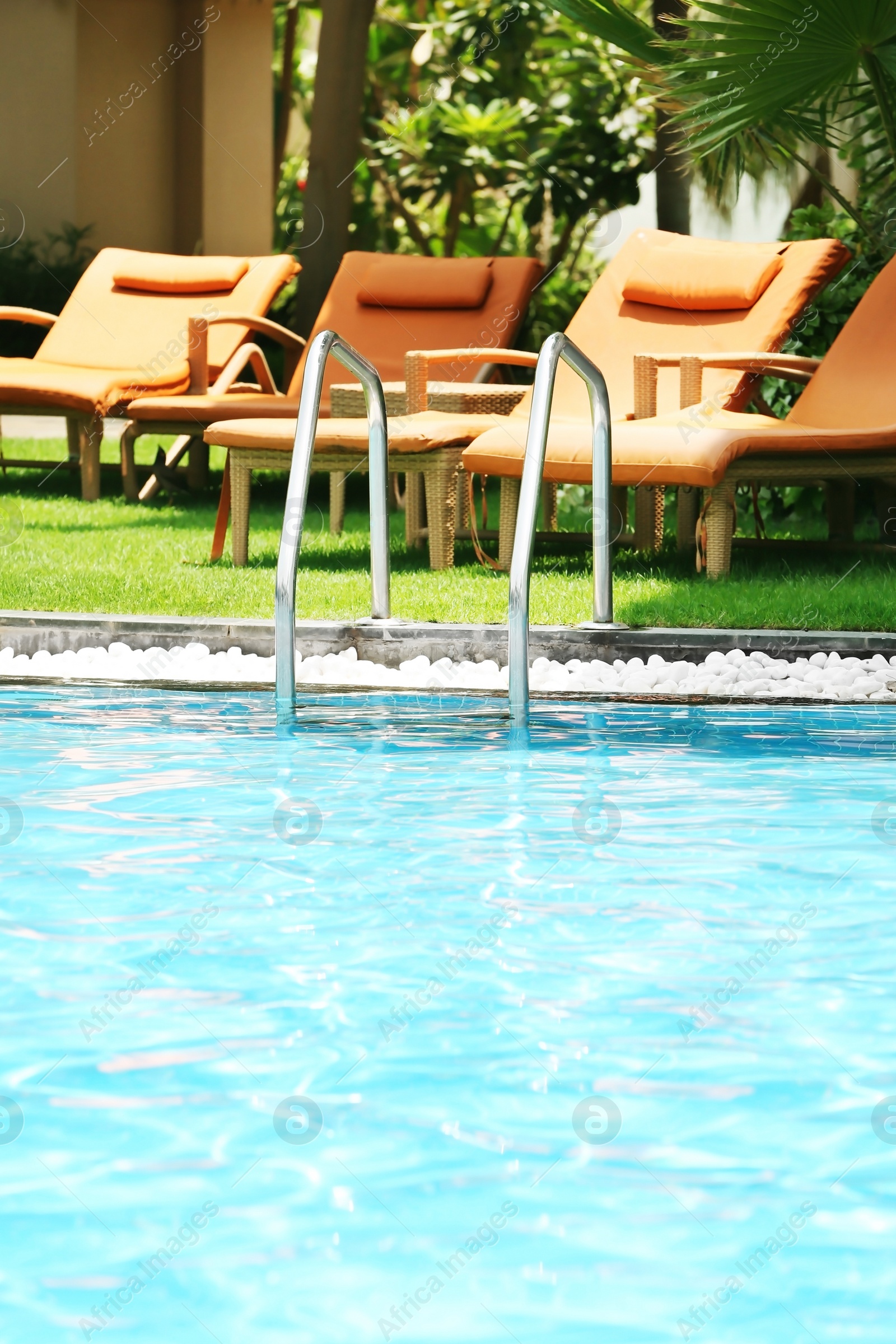 Photo of Sunbeds near modern swimming pool at resort