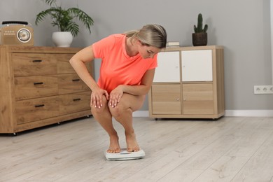 Woman in sportswear standing on floor scales at home