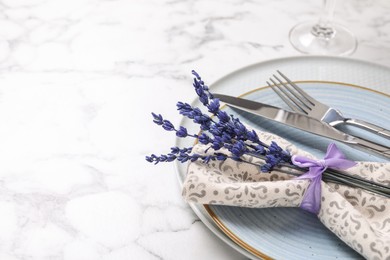Photo of Cutlery, napkin, plates and preserved lavender flowers on white marble table, closeup. Space for text
