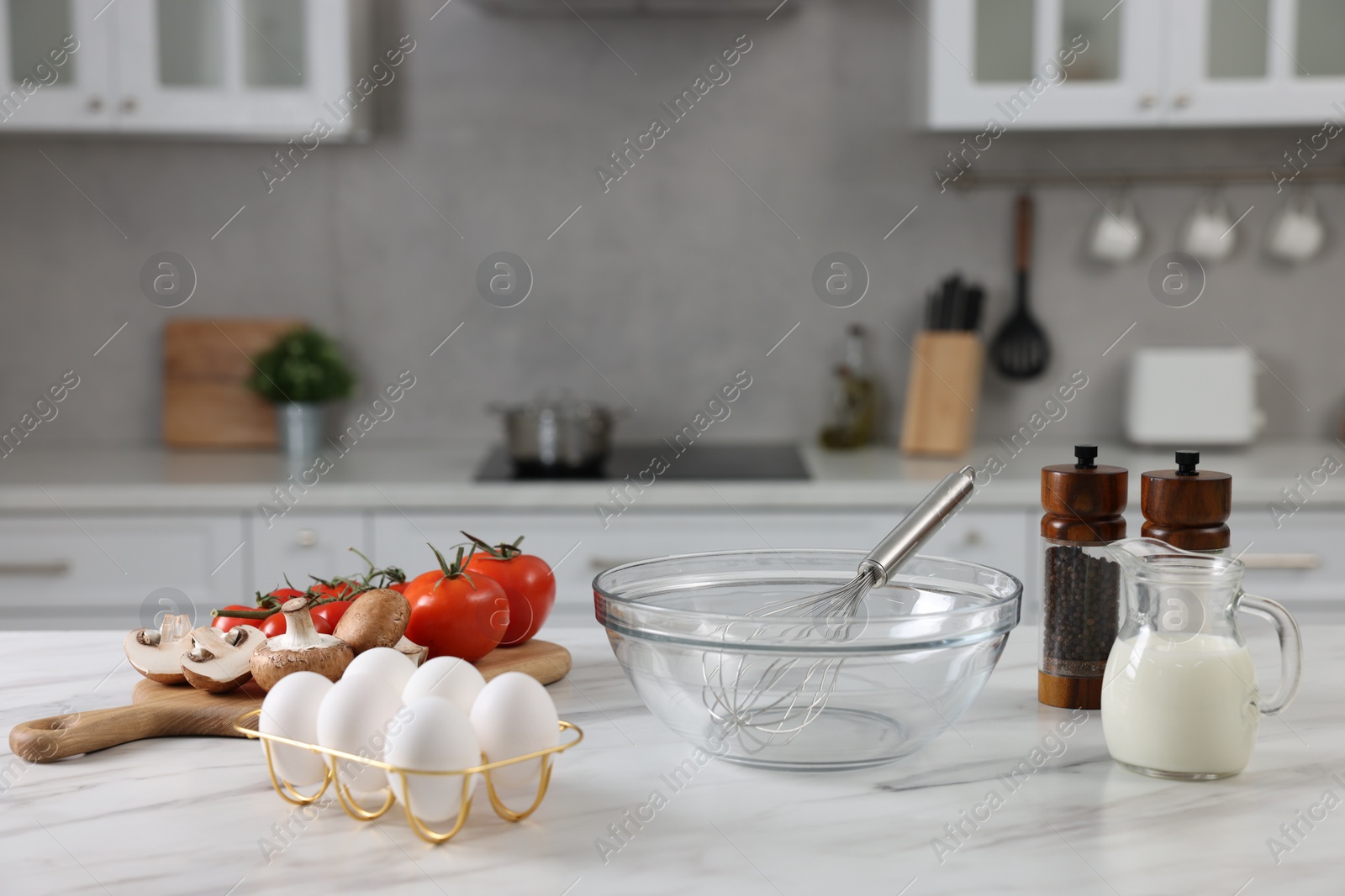 Photo of Whisk, bowl, and different ingredients on white marble table indoors