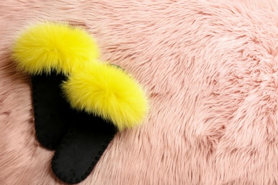 Photo of Pair of soft slippers on pink faux fur, flat lay. Space for text