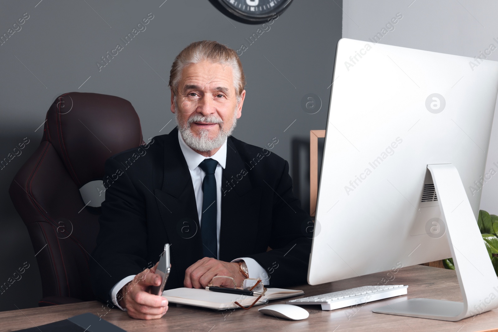 Photo of Happy senior boss working in his office