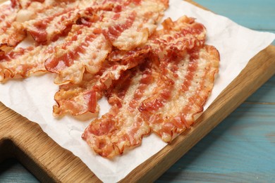 Photo of Delicious fried bacon slices on blue wooden table, closeup