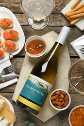 Photo of Flat lay composition with bottle of white wine and snacks on wooden table