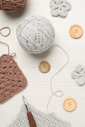 Photo of Flat lay composition with knitting threads and crochet hook on white wooden table
