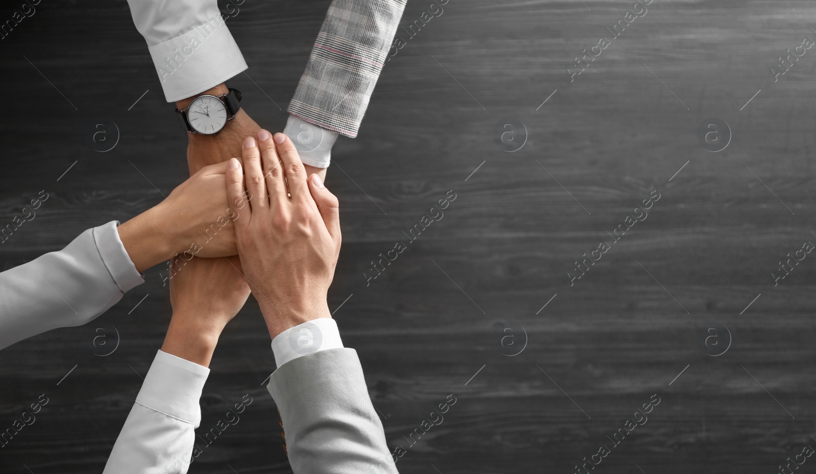 People holding hands together over grey wooden background, top view with space for text. Unity concept Photo of People holding hands together over grey wooden background, top view with space for text. Unity concept