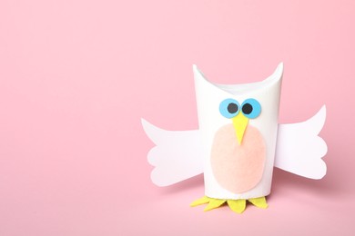Toy owl made of toilet paper hub on pink background. Space for text