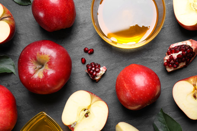 Photo of Honey, apples and pomegranate on black table, flat lay. Rosh Hashanah holiday