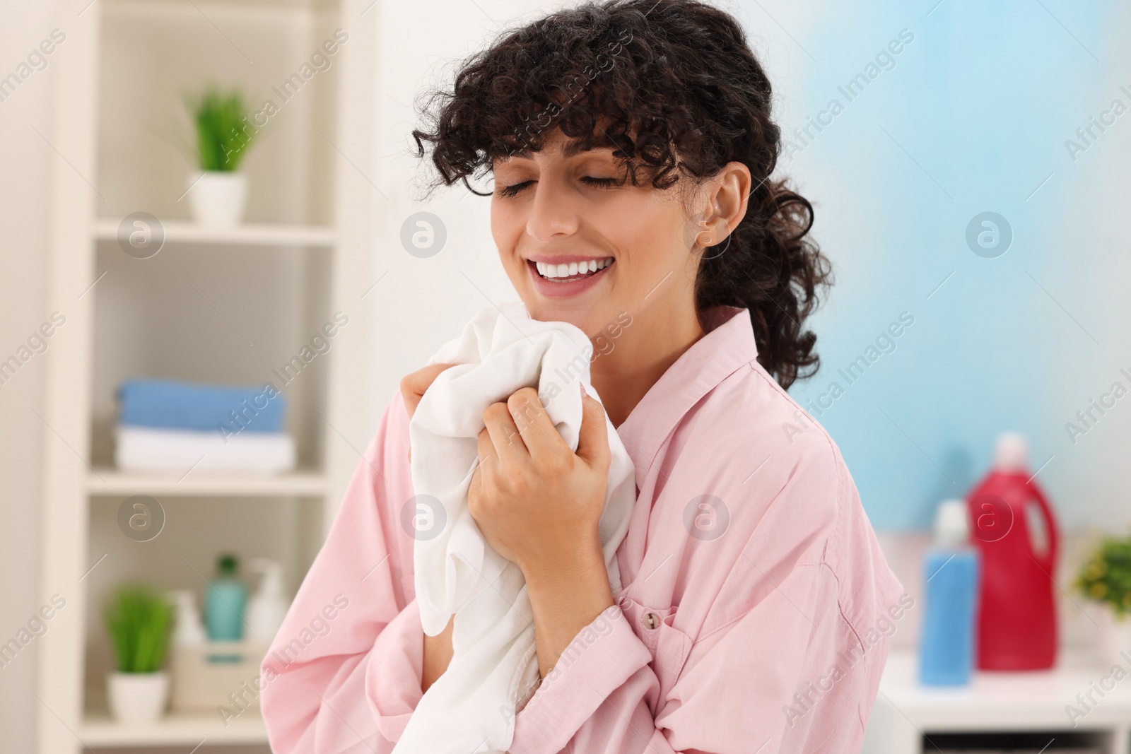 Photo of Beautiful woman with clean laundry at home