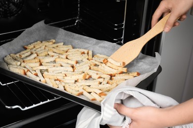 Woman taking baking pan with hard chucks out of oven, closeup