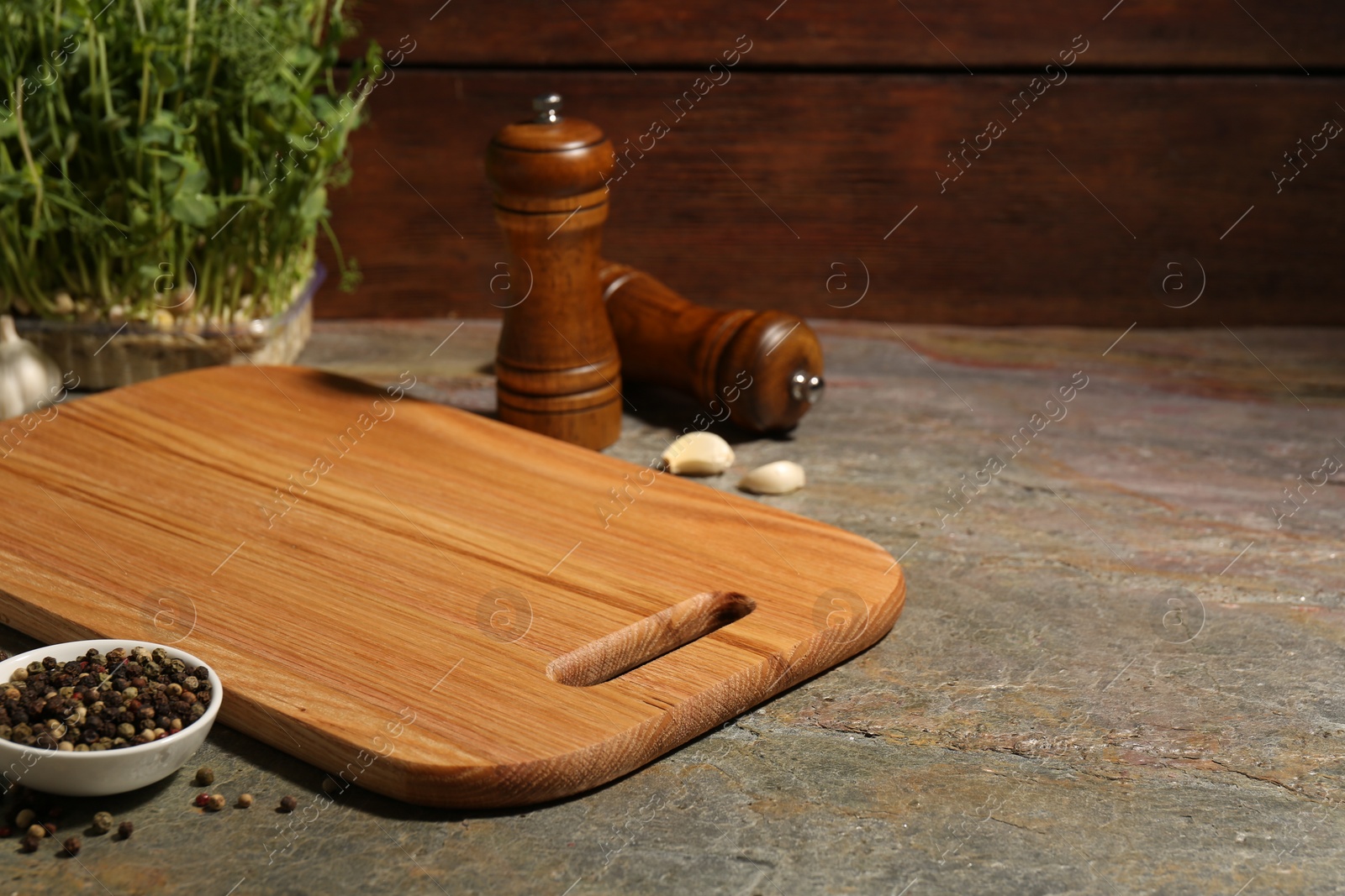 Photo of Wooden cutting board and spices on textured table, closeup. Space for text