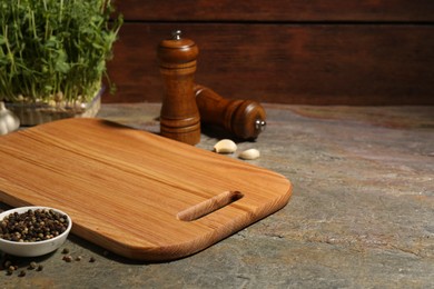 Photo of Wooden cutting board and spices on textured table, closeup. Space for text