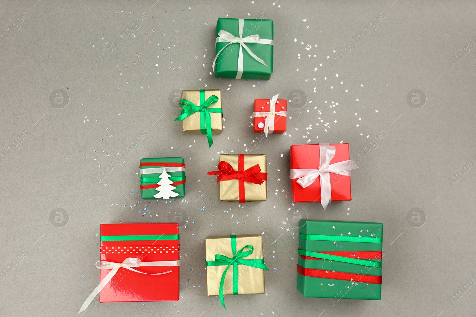 Photo of Christmas tree shape of gift boxes on grey background, flat lay. Space for text