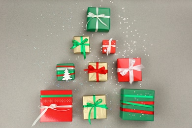 Photo of Christmas tree shape of gift boxes on grey background, flat lay. Space for text