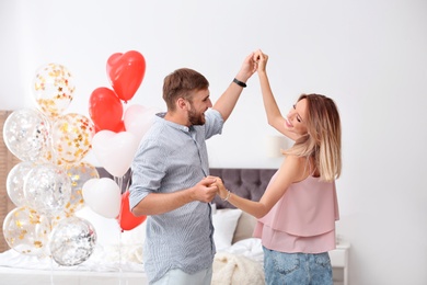 Young couple with air balloons in bedroom. Celebration of Saint Valentine's Day