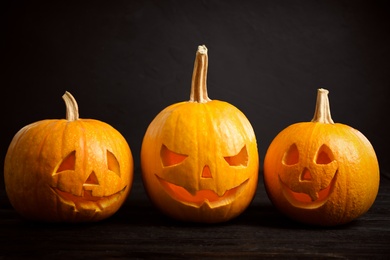 Spooky Jack pumpkin head lanterns on wooden table against black background. Halloween decoration