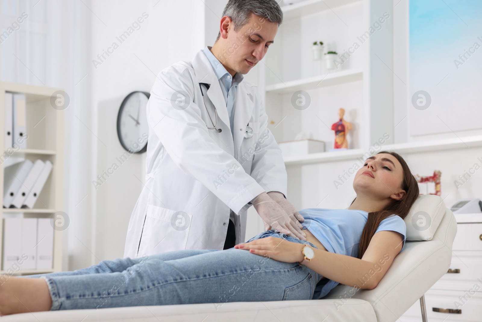 Photo of Gastroenterologist examining patient with stomach pain on couch in clinic