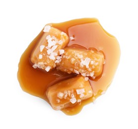 Photo of Yummy caramel candies and sea salt isolated on white, top view