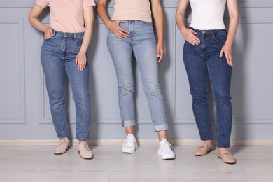 Photo of Women in stylish jeans near light grey wall indoors, closeup