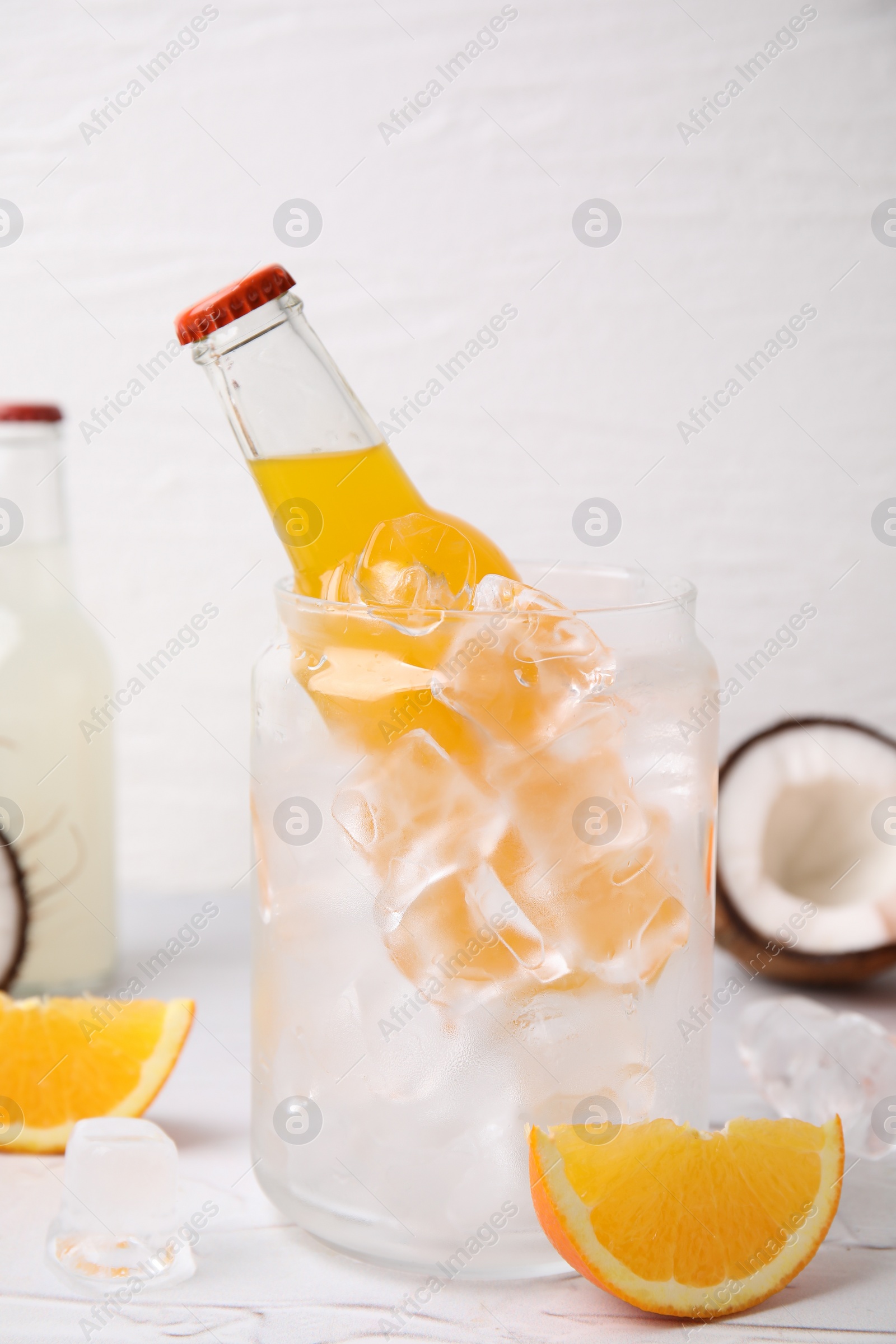 Photo of Tasty kombucha in bottle, glass with ice and fresh fruits on white table