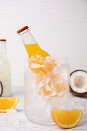 Photo of Tasty kombucha in bottle, glass with ice and fresh fruits on white table