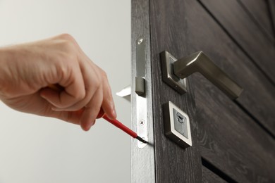 Photo of Worker with screwdriver repairing door lock indoors, closeup