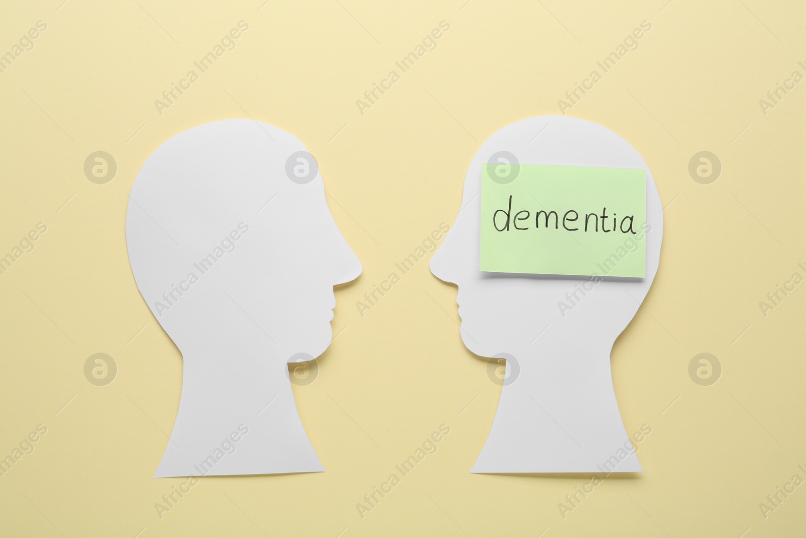 Photo of Human heads cutout with word Dementia on beige background, flat lay