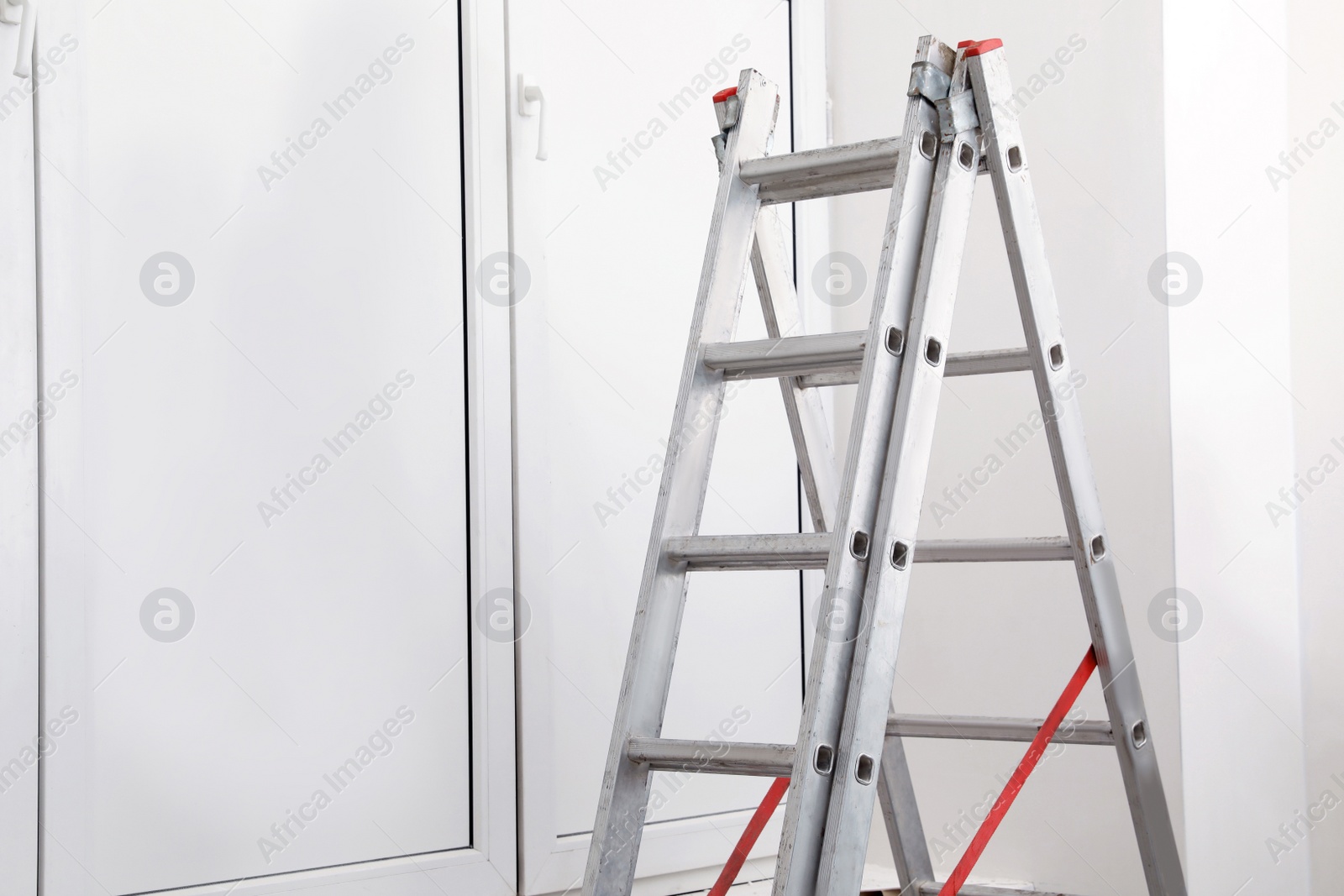 Photo of Metal folding ladder near closed window indoors. Space for text