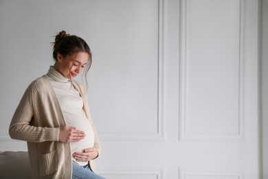 Photo of Young pregnant woman at home. Space for text