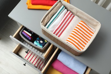 Photo of Chest of drawers with different folded clothes indoors, top view